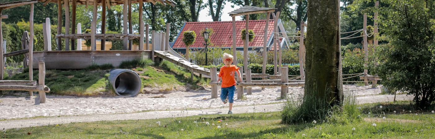 Kind rent langs een speeltuin op het peutervriendelijke vakantiepark Sandberghe