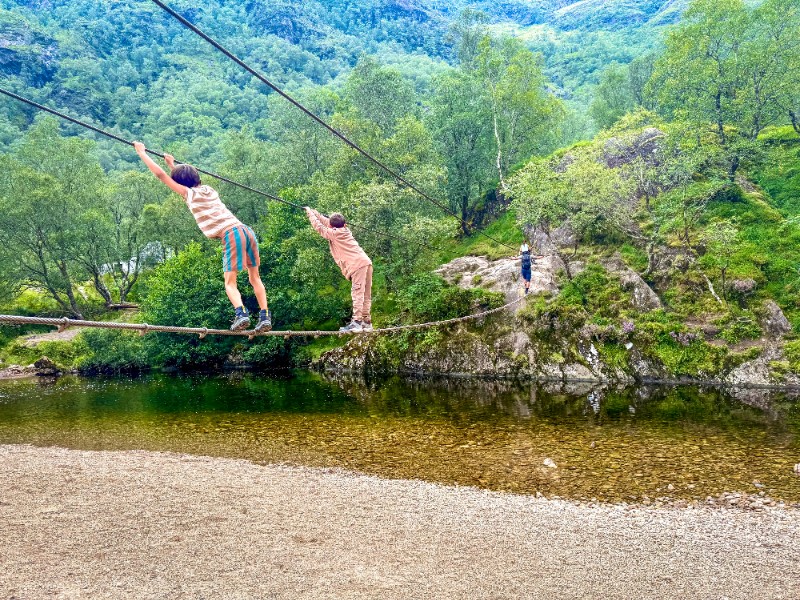 gezin steekt water over via touwbrug