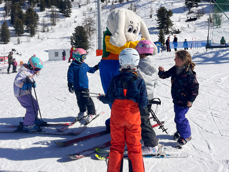 De mascotte van Nendaz met de kids op de skipiste