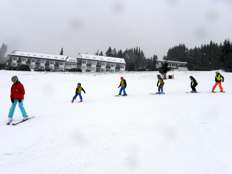 In een keurige rij komt het skiklasje de berg af