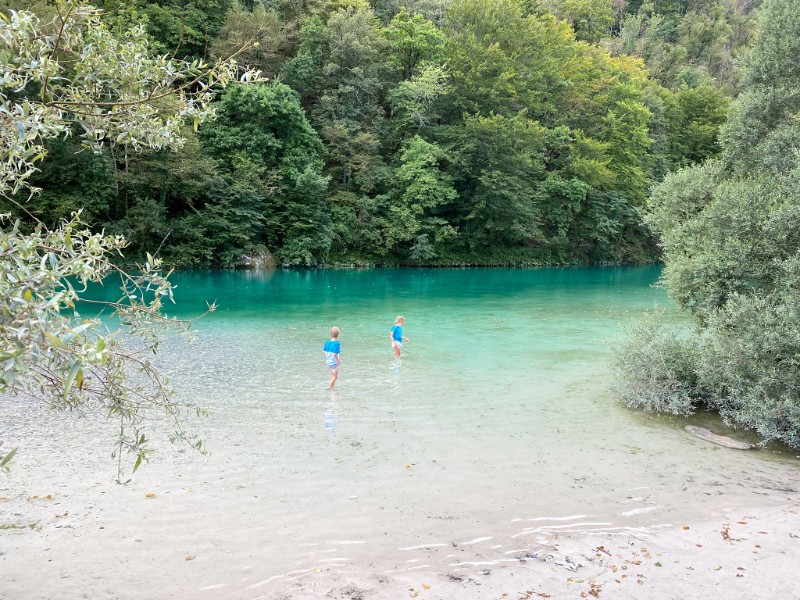 Onze kinderen spelen tijdens een bewolkte ochtend in de rivier de Soca in de Sloveense Soca Vallei