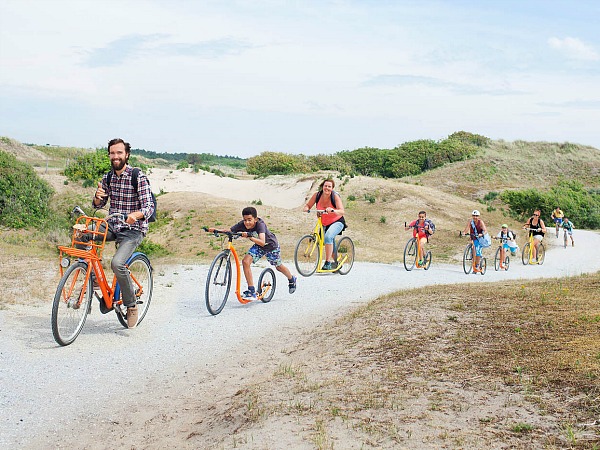 Gezin rijdt op de fiets en step door de duinen