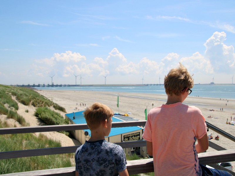 Zeb en Tycho kijken uit over het strand naar de Deltawerken