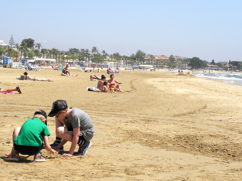 Zeb en Tycho bouwen een zandkasteel op het brede strand