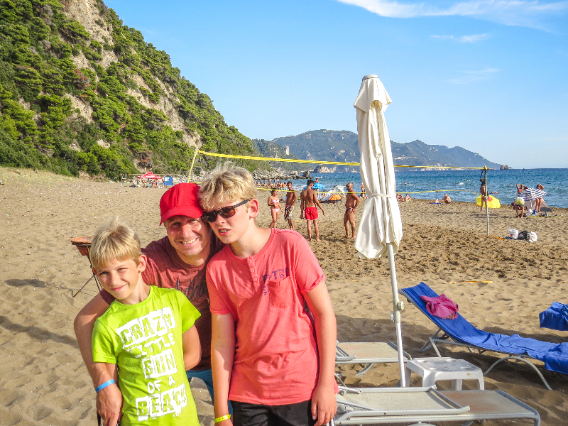 Patrick en de jongens op zandstrand Glyfada op Corfu, Griekenland met kinderen