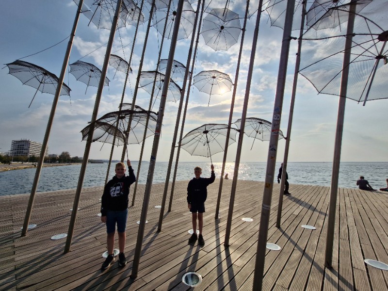 De jongens houden een paraplu vast op de boulevard van Thessaloniki