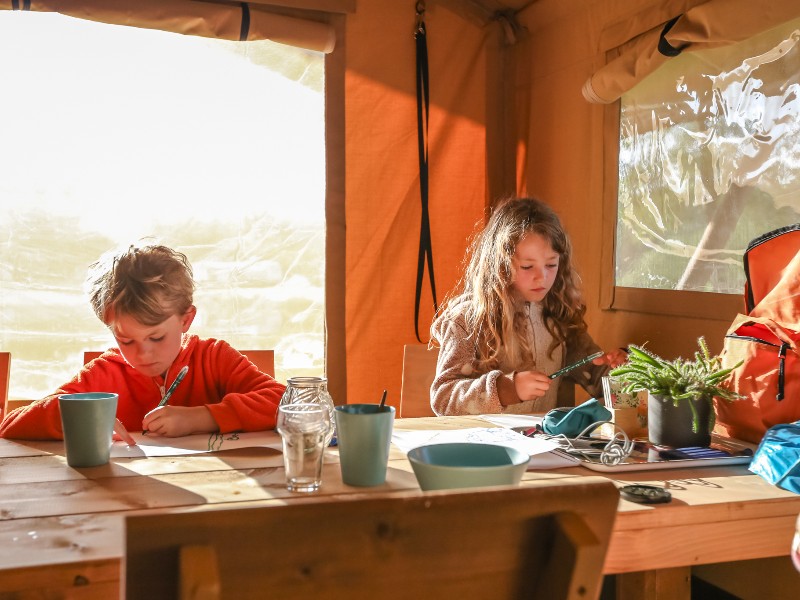 De kinderen van Elisabeth zitten 'sochtends lekker te kleuren aan de eettafel in hun safaritent van Vodatent