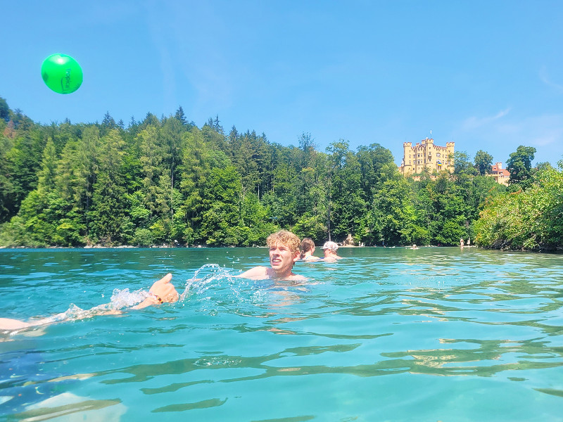 Zeb zwemt in de Alpsee met zicht op schloss Hohenschwangau