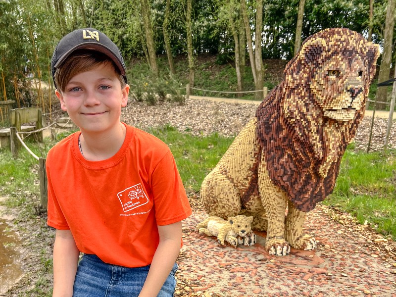 De zoon van Barbara bij een beeld van een leeuw tijdens Expeditie Bricks in ZooParc Overloon