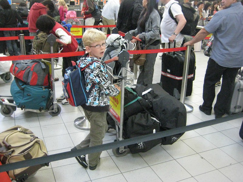 Zeb met de bagage in de rij op schiphol